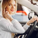 Lady in a car salon. Woman buying the car. Blonde in a white shirt