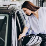 Young woman in a car showroom choosing a car